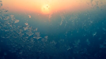 Obraz premium Snowflakes on windowpane at sunset with orange glow frost