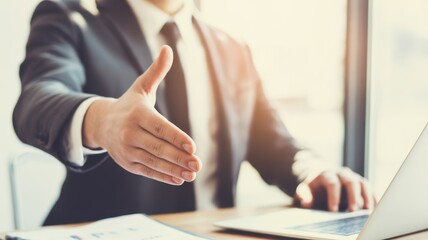 Business handshake gesture: A professional in a tailored suit extends a welcoming hand, symbolizing partnership, agreement, and the beginning of a business deal.