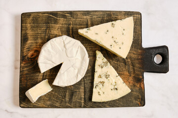 Cheese on wooden board arranged in different shapes and sizes during a casual snack time