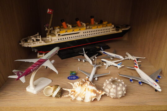 Collection of model airplanes and a ship displayed on a wooden shelf with seashells
