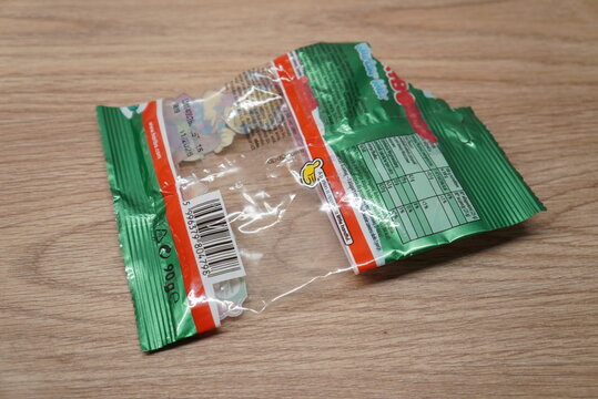Empty green candy wrapper with nutritional information and barcode on wooden surface