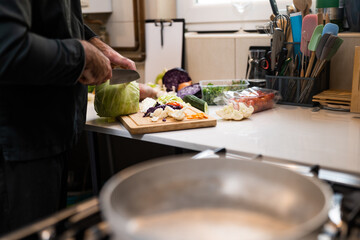 Close up of professional chef preparing ingredients for vegetarian meal in restaurant's kitchen. He is cutting cabbage.