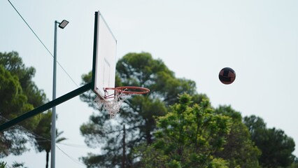 Basketball ball in mid air approaching a hoop and backboard at an outdoor court © FranciscoJavier