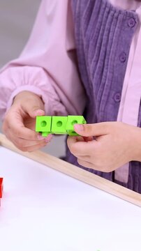 Child Connecting Green Math Manipulative Cubes for Educational Counting Activity