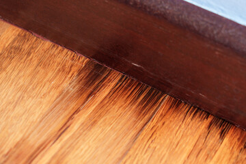 Rotting laminate floor with wooden baseboards in a damp room. Damaged decayed material
