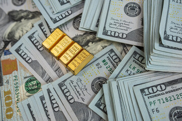 Two gold bars on stacks of US dollar bills symbolizing wealth, financial success and investment growth