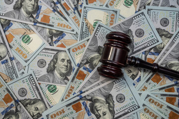 Wooden gavel on a background of US dollar banknotes, representing financial judgment.