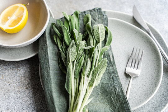 Overhead view of a place setting with fresh sage leaves and half a lemon