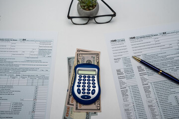 Close up of 1040 form with scattered US dollars, glasses and pen &mdash; 2025 tax documents