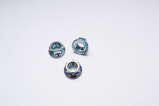 Pile of zinc-plated serrated flange hex nuts on a white background.