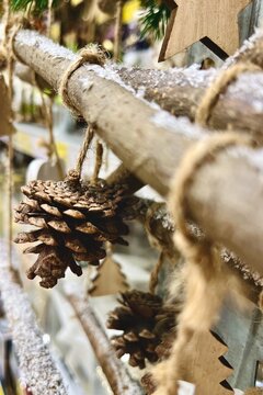 Close-up of a Christmas pinecone ornament hanging on a wooden branch
