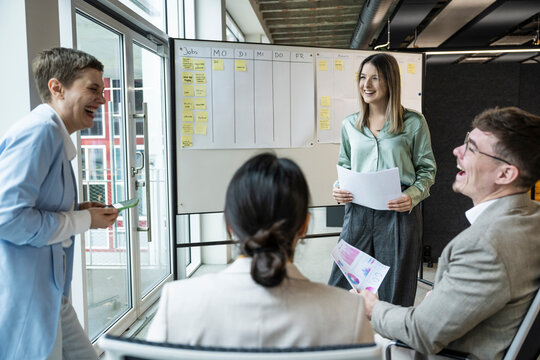 Team collaborating and smiling during business presentation in modern office