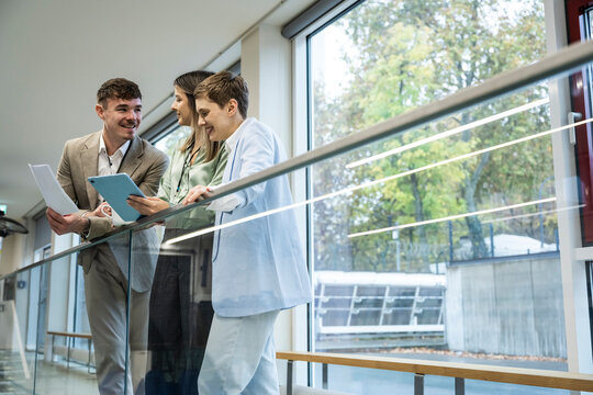 Business team discussing project with tablet and documents in modern office