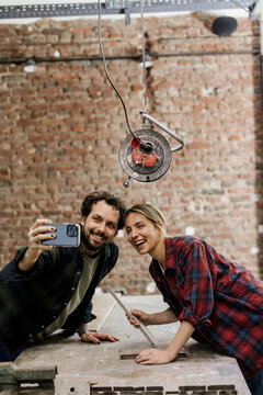 Smiling couple taking a selfie during renovation at construction site