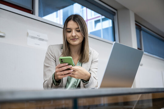 Businessperson messaging with mobile phone at a modern office desk