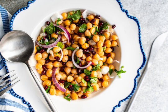 Close-up Overhead view of a bowl of chickpea, red onion, pomegranate and coriander salad on a table