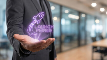 Startup business high level planning concept visualized with glowing launch phase hologram over open hand in modern office interior