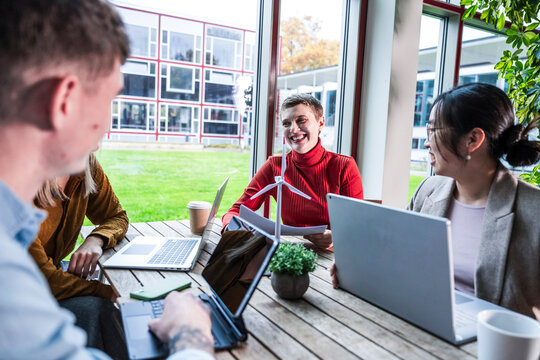 Teamwork meeting in modern office with windmill model and laptops
