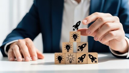 Businessman building a pyramid with wooden blocks featuring lightbulb and rocket ship symbols