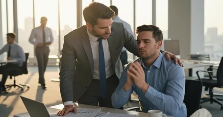 Businessman supporting his stressed colleague in a modern office environment