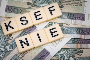 Blocks with the abbreviation KSEF NO, standing for negatives about National E-invoice System, are placed against a background of loosely spread Polish 100 PLN banknotes. 