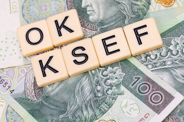 Blocks with the abbreviation OK KSEF, standing for positives about National E-invoice System, are placed against a background of loosely spread Polish 100 PLN banknotes. 