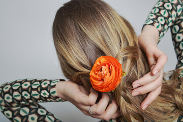 Detailaufnahme einer Person mit blondem Haar, das zu einer kunstvollen Form gebunden ist, in die...