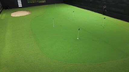 Indoor golf practice area showcasing continuous putting action with multiple golf balls and targets on vibrant green turf surface