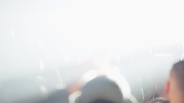 People in concert crowd raise hands and smartphones and moshing during energetic live performance with blue lighting