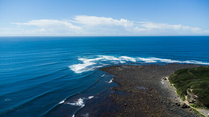 Aerial view of a rock shelf jutting into the ocean