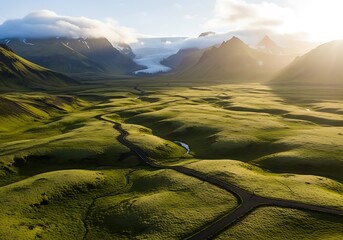 Dramatic aerial view captures winding road through vibrant green glacial valley bathed in golden sunlight