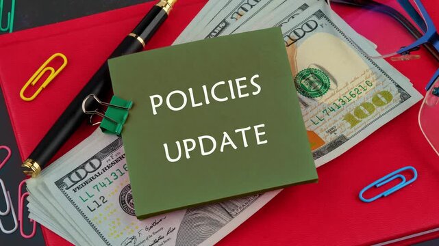 Animation of the appearance of the conceptual text of POLICIES UPDATE on a green sticker on a background of money. Business concept