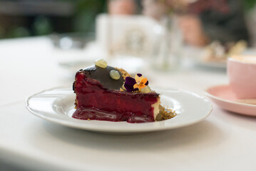 piece of chocolate fruit with berries mousse cake is decorated with flowers on a plate