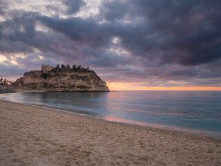 Tropea cliff sanctuary at dusk in Calabria, illuminated historic church on rocky promontory above Tyrrhenian Sea, dramatic clouds, coastal landmark, southern Italy travel destination