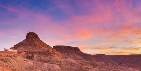 Sunset light over Ksar Guermassa ancient fortified village in Dahar mountains, Tataouine region Tunisia, desert landscape, dramatic sky, cultural heritage, travel