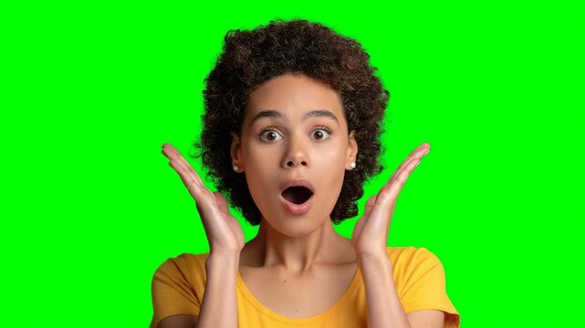 A shocked and excited young woman isolated on green screen chroma key background