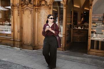 Woman walking with coffee in front of wooden shop