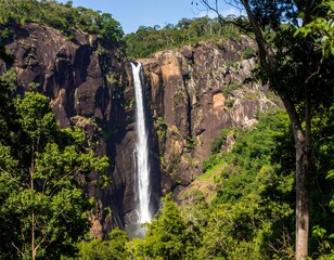 Waterfall cascading down rocky cliffs surrounded by lush green jungle