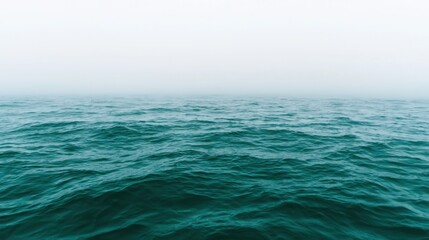 Obraz premium A vast expanse of deep blue ocean meets a light gray sky.