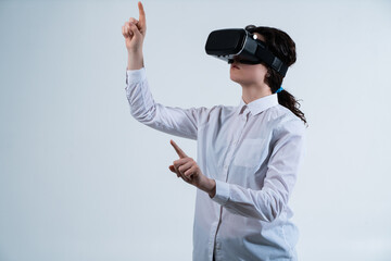Woman wearing virtual reality headset and interacting with virtual interface using hand gestures while standing against clean white studio background