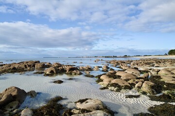 Rocky tidal flats at low tide with rippled sand and clear pools &mdash; calm coastal landscape