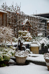 Winter Garden Scene With Snow Covered Fences, Birdhouse, Baskets, And Rustic Water Pump In Backyard