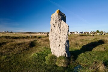 Ancient menhir standing stone in open field under clear blue sky &mdash; prehistoric megalith with copy space