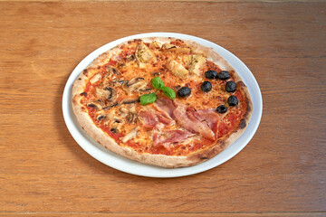 Pizza Four seasons on white plat on wooden table