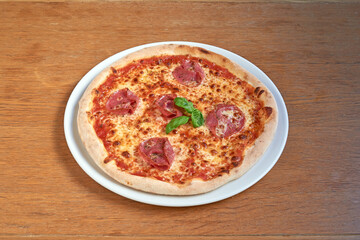 Pizza Salami on white plat on wooden table