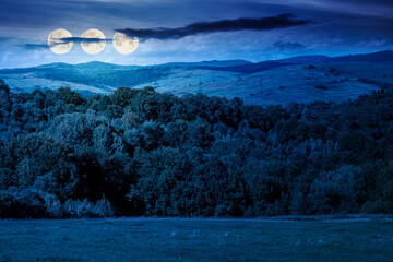 rural landscape in mountain at night. grass on rolling hill and peak in autumn full harvest moon light. countryside scenery with alpine pasture. inner strength to overcome fear, loneliness in darkness