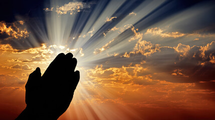 Hands clasped in prayer against a dramatic sunset sky.