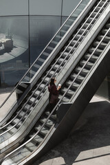 Woman with coffee on modern escalator in building