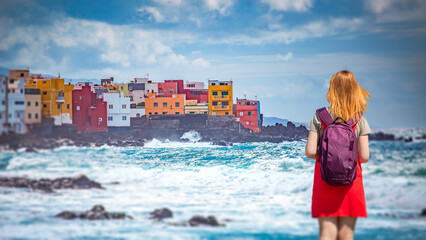 A woman in a red dress in Tenerife against the backdrop of colorful houses