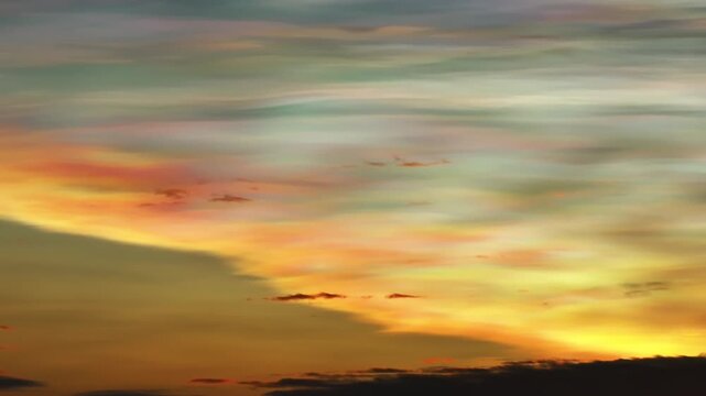 Aerial view of vibrant nacreous clouds shimmering with iridescent hues of pink, gold, and green paint the sky, creating a surreal and ethereal spectacle, Lapland, Finland.
